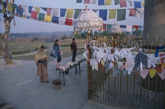 NEPAL, Lumbini, Pilgrims in front of the Ashoka pillar dating about 320 BC beside pond at sacred
