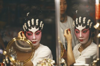 HONG KONG, General, "Performer in Chinese opera applying make up, reflected in mirror at side."