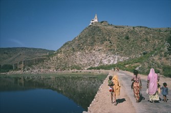 INDIA, Rajasthan, General, Women and children walking beside water reservoir tank twenty miles