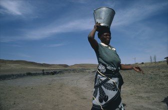LESOTHO, Water, Woman carrying water from well on her head.