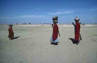 INDIA, Rajasthan, Thar Desert, Women returning from village well carrying water on their heads.