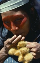 ECUADOR, Amazon, Auca Indian woman with achole plant from which the red colouring used as face
