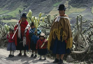 ECUADOR, Cotopaxi, Zumbahua, Family on roadside returning home from Palm Sunday Mass holding woven