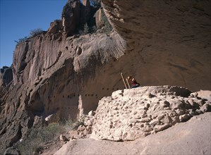 20059230 USA New Mexico Bandelier National Monument.  Visitor climbing ladder amongst caves.