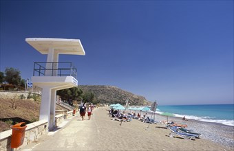CYPRUS, Pissouri Bay, Sunbathers on narrow sand and pebble beach with people walking along