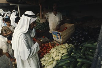 QATAR, Doha, "Man at vegetable stall in souk selling courgettes, aubergines, squash and tomatoes."