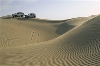 UAE, Baniyes Desert, Dune driving.  Two jeeps on ridge of wind rippled sand dune.