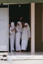 INDONESIA, Java, Muslim college girls dressed in white standing at a door entrance.