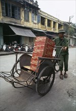 VIETNAM, Hanoi, Man walking in street with a cyclo filled with coke boxes