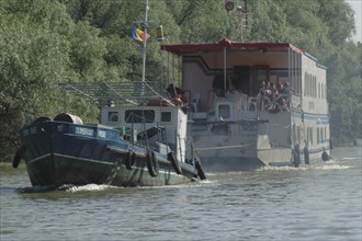 ROMANIA, Tulcea, Danube Delta, Boat with tourists towed by a tug in Danube Delta Biosphere Reserve
