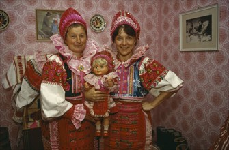 SLOVAKIA, Carpathian Mountains, Small Tatras, Helpa.  Two women holding doll all dressed in
