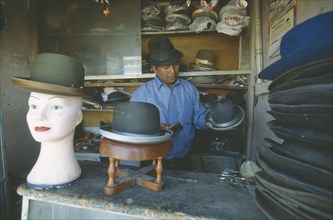 BOLIVIA, La Paz, El Alto.  Hat maker in La Ceja making traditional brown and grey bowler hats known