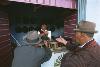 BOLIVIA, La Paz, El Alto, Hat maker in La Ceja exchanging money with customers.