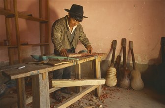 BOLIVIA, Chuquisaca, Tarabuco, Charango musical instrument maker at workbench.