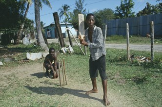 WEST INDIES, Jamaica, Clarendon, Boys playing cricket with home made bat and wickets.