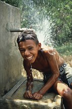 DOMINICAN REPUBLIC, Children, Boy cooling off under a standpipe.