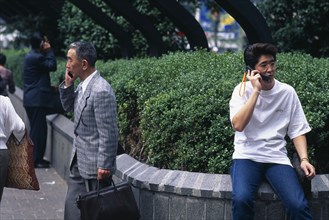 JAPAN, Shibuya, Tokyo, Three men ranging in age talking on mobile phones.