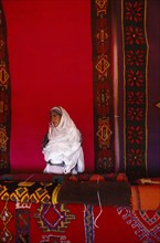 WESTERN SAHARA, Markets, Textiles, Woman with traditional carpets.