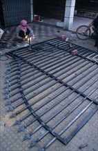 CAMBODIA, Siem Reap, Man welding a metal gate which is lying on the ground
