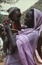 SUDAN, Kordofan, Nomadic African Arab woman holding baby.