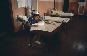 WEST INDIES, Grenada, Health, Hospital interior with nurse writing notes and patient lying on bed