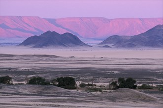 NAMIBIA, Namib Desert, Desert mountains and plains with pink and purple sky overhead