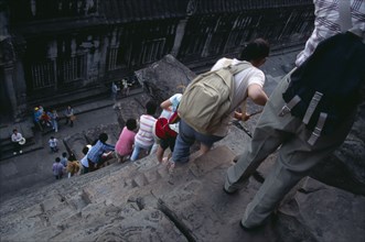 CAMBODIA, Siem Reap Province, Angkor Wat, Line of tourists climbing down steep and narrow steps of