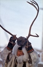 RUSSIA, Siberia, Yakutia, Native boy dressed in furs playing with reindeer antlers.