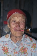 RUSSIA, Siberia, Lake Baikal, Portrait of elderly Buryat woman smoking pipe.