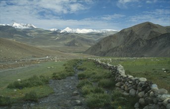 INDIA, Ladakh, Himalayas, Mountain landscape with rocky stream through valley floor in foreground.