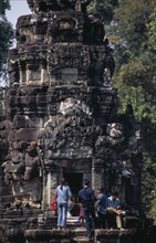 CAMBODIA, Siem Reap Province, Angkor, Neak Pean.  Tourists lighting incense at entrance to small