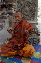 CAMBODIA, Siem Reap Province, Angkor Thom, Buddhist monk chanting from Sanskrit prayers inscribed