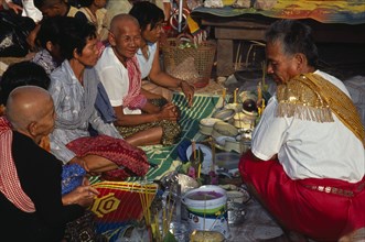 CAMBODIA, Siem Reap, Angkor Wat, Shaman at ceremony smelling the offerings of food brought by the