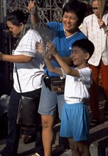 MALAYSIA, Penang, Georgetown, Kuan Yin Teng or Temple of Mercy with young boy releasing a caged