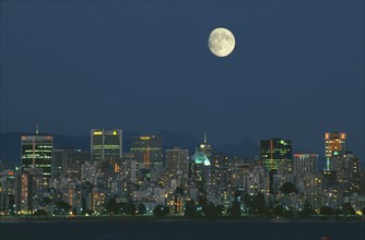 CANADA, British Columbia, Vancouver, Full moon over downtown Vancouver at dusk.