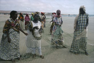 SOMALIA, Industry, Settled nomad women mending fishing net on shore of beach.