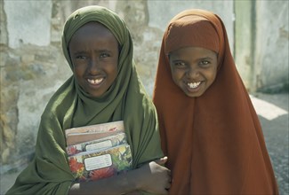 SOMALIA, Baidoa, Portrait of two schoolgirls with covered heads carrying school books.
