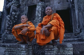 CAMBODIA, Siem Reap, Angkor Thom, Bayon Temple with two monks sitting on the upper level
