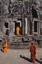 CAMBODIA, Siem Reap, Angkor Thom, Bayon Temple with three monks taking photographs of each other on