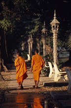 CAMBODIA, Siem Reap, Siem Reap Town, Two monks walking along the path lined with stone lanterns