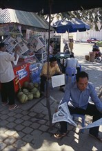 CAMBODIA, Siem Reap, Men reading newspapers at a drinks stall