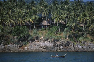 THAILAND, Krabi, Koh Lanta Yai, The Narima Spa Resort chalets amongst coconut palm trees with a man