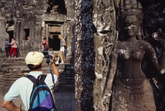 CAMBODIA, Siem Reap Province, Angkor Thom, The Bayon.  Tourists with cameras and videos with bas