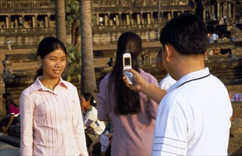 CAMBODIA, Angkor Wat, Man photographing a girl with his mobile phone