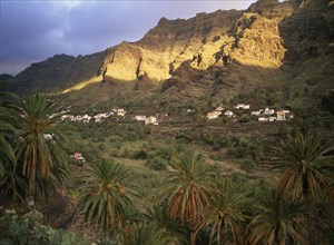 SPAIN, Canary Islands, La Gomera, Valle Gran Rey.  Houses on terraced hillside at foot of sheer