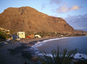 SPAIN, Canary Islands, La Gomera, Valle Gran Rey.  Crowds on black volcanic sand beach at sunset.