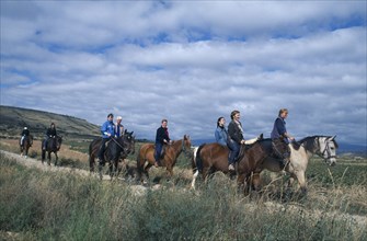 SPAIN, La Rioja, Tourist group trekking on horseback through rural landscape.