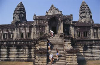 CAMBODIA, Siem Reap Province, Angkor Wat, Western tourists climbing steep and narrow set of steps