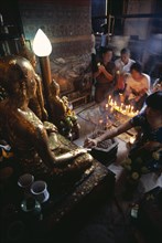 THAILAND, South, Bangkok, Wat Pho small shrine beside the reclining Buddha with devotees making