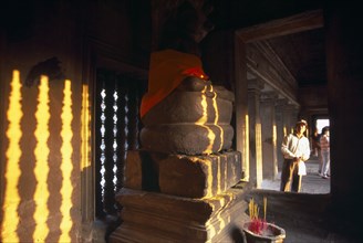 CAMBODIA, Siem Reap Province, Angkor Wat, Tourist looking into interior of shrine in upper or third